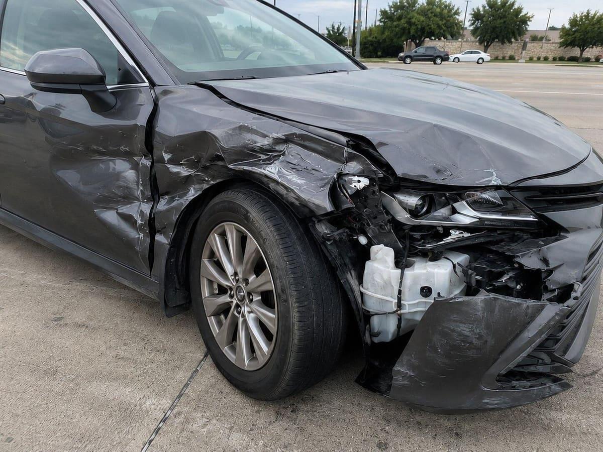 Passenger-side front-quarter damage to the claimant’s gray sedan after the collision