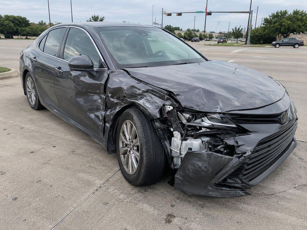 Front passenger-side view of the damaged sedan at the intersection